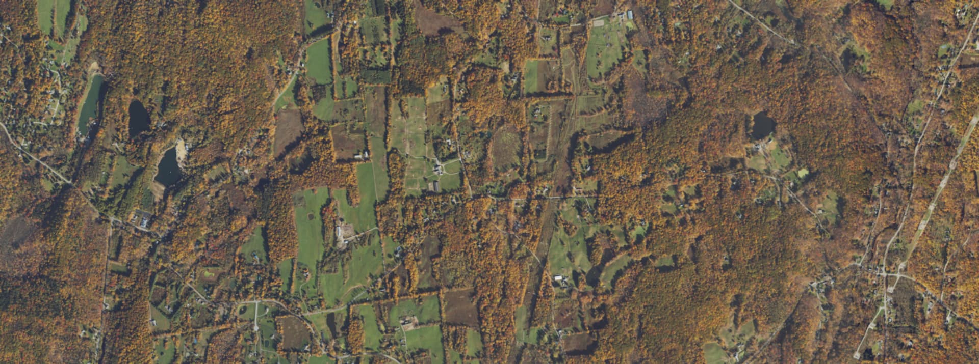 Aerial survey view over Clinton Corners, NY, showing the crossroads hamlet, orchards and heavy tree cover