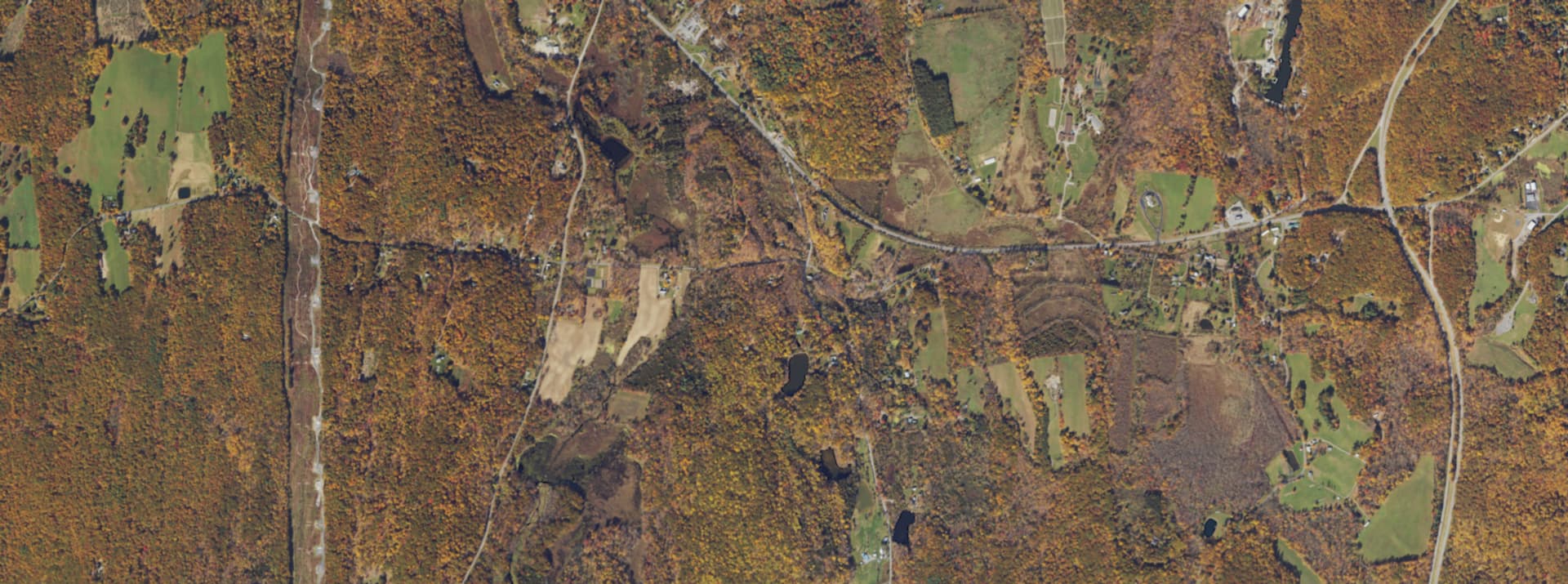 Aerial survey view over Milan, NY, showing rural back roads, open fields and dense woodland