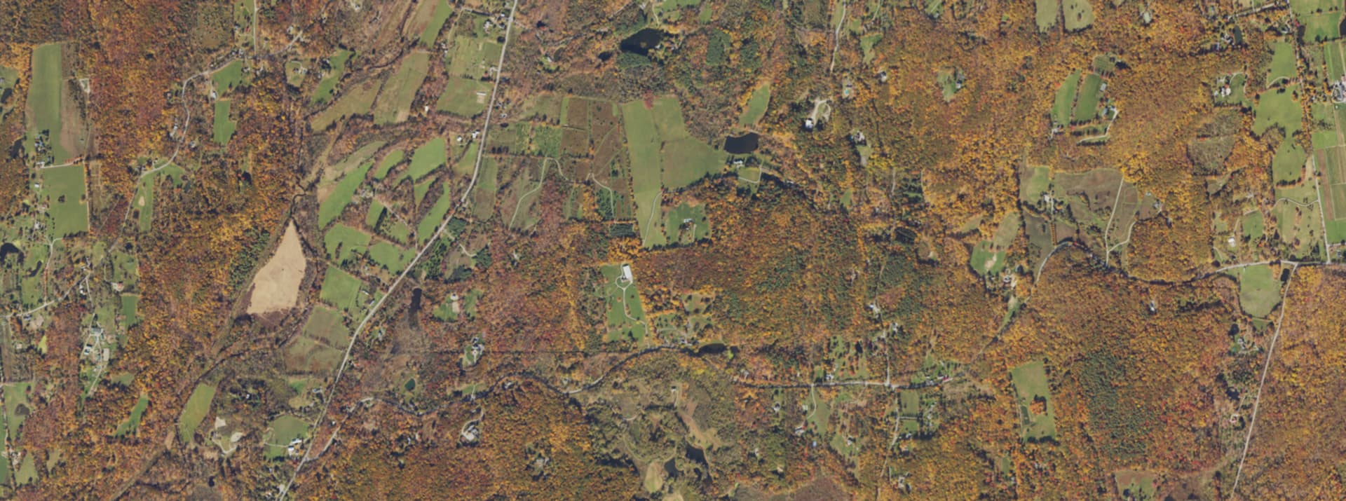 Aerial survey view over Millbrook, NY, showing the road network, tree cover and surrounding countryside