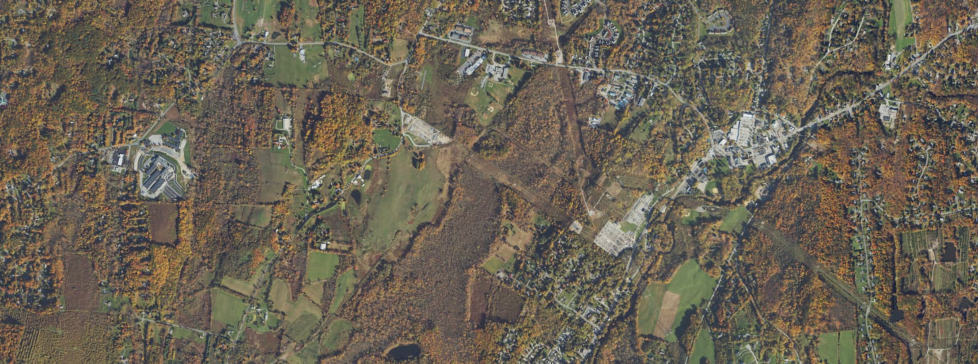 Aerial survey view over Pleasant Valley, NY, showing the road network, tree cover and surrounding countryside