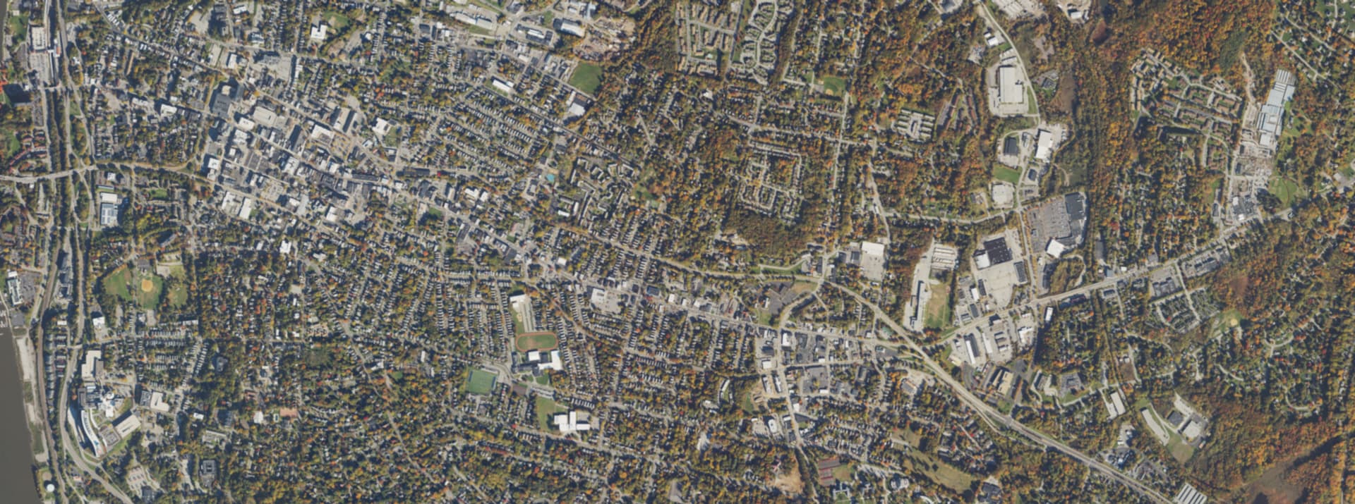 Aerial survey view over Poughkeepsie, NY, showing the street grid, tree cover and the Hudson River
