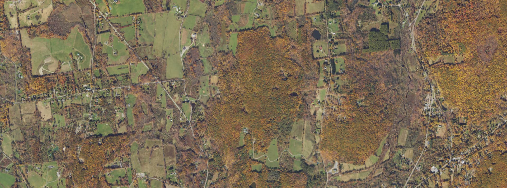 Aerial survey view over Stanfordville, NY, showing the hamlet, farm fields and wooded lots